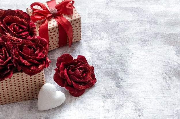 Cadeau de la Saint-Valentin avec des roses décoratives et un coeur blanc sur l'espace de copie de fond clair.