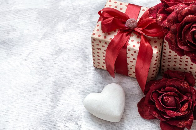 Cadeau de la Saint-Valentin avec des roses décoratives et un coeur blanc sur l'espace de copie de fond clair.
