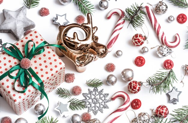 Cadeaux, branches de sapin, décorations rouges sur fond blanc.