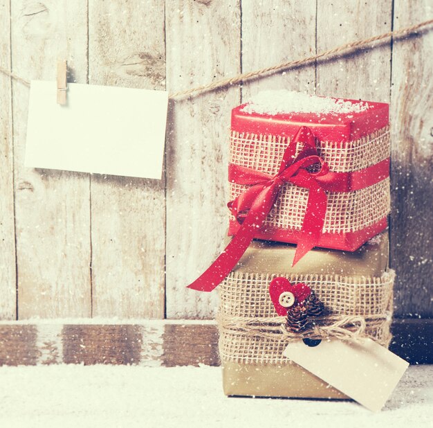 Cadeaux enveloppés dans un tissu avec un arc rouge et une enveloppe sur une corde