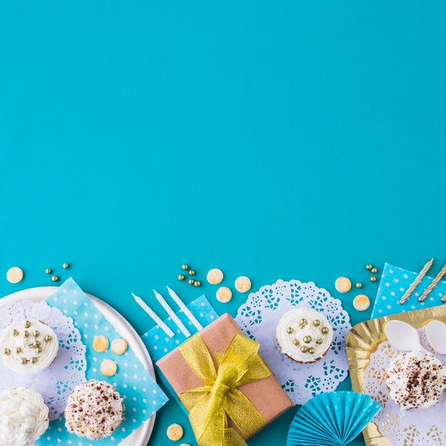 Cadeaux avec des muffins sur une assiette et un plateau au bord du fond bleu