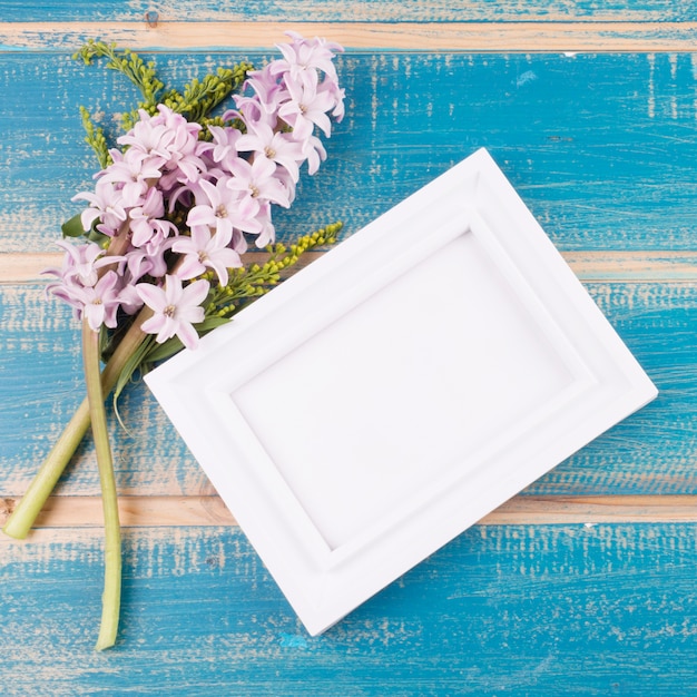 Photo gratuite cadre blanc avec des fleurs sur la table