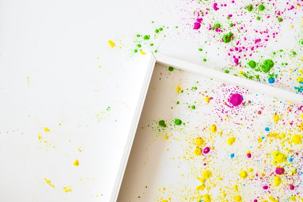 Un cadre en bois vide sur fond blanc avec de la poudre de couleur holi