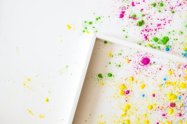 Un cadre en bois vide sur fond blanc avec de la poudre de couleur holi