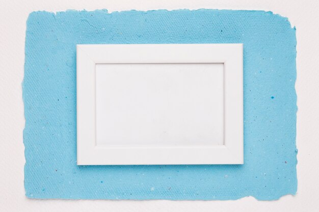 Un cadre de bordure blanche vide sur du papier bleu sur fond blanc