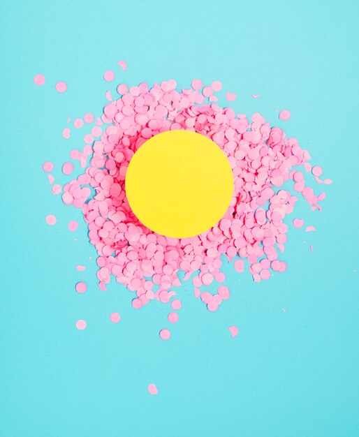 Cadre de cercle blanc jaune au-dessus des petits confettis roses festifs sur fond bleu