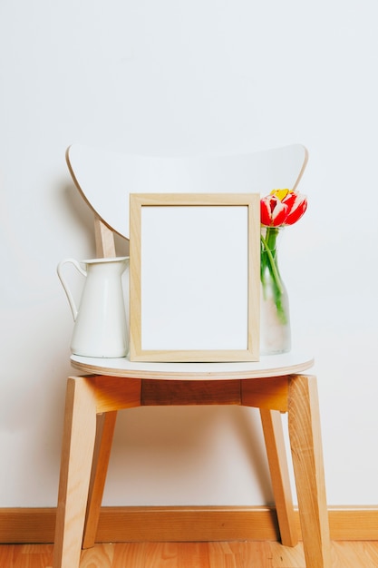 Photo gratuite cadre sur une chaise entre vase et pichet