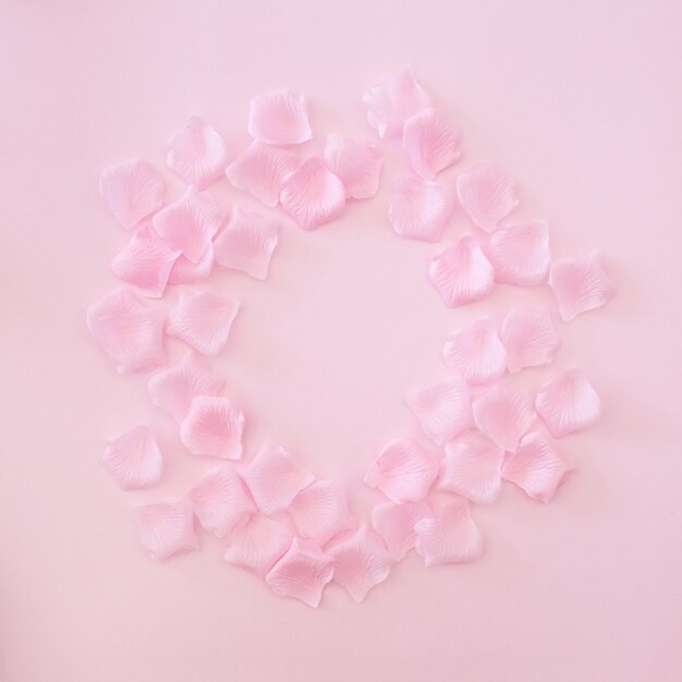 cadre composé de pétales de roses roses sur fond rose