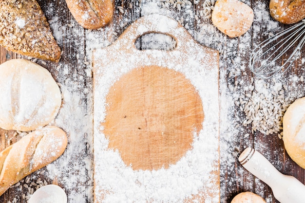 Cadre à farine blanche sur planche à découper entouré de pains