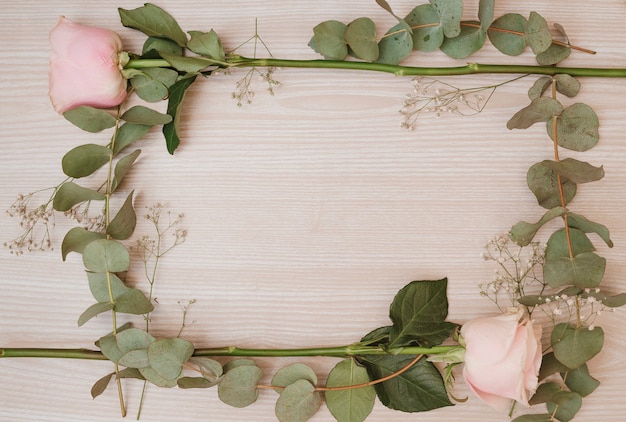 Photo gratuite cadre de fleurs rose rose sur un bureau en bois