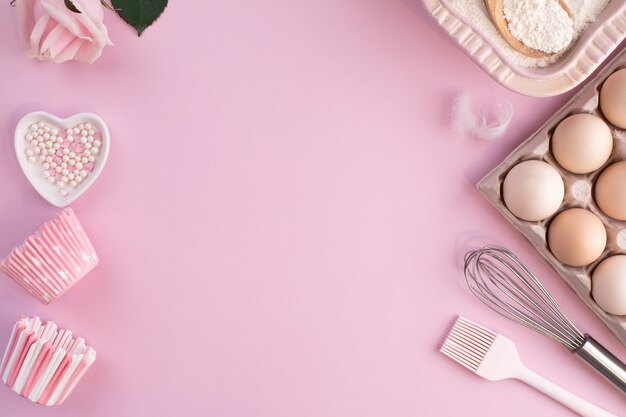 Cadre d'ingrédients alimentaires pour la cuisson sur un fond pastel légèrement rose. Cuisson à plat avec espace de copie. Vue de dessus. Concept de cuisson. pose à plat