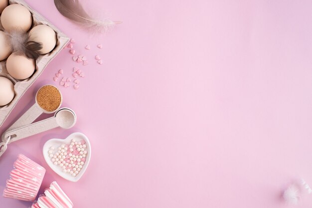 Cadre d'ingrédients alimentaires pour la cuisson sur une table pastel légèrement rose. Cuisson à plat avec espace de copie. Vue de dessus. Concept de cuisson. pose à plat