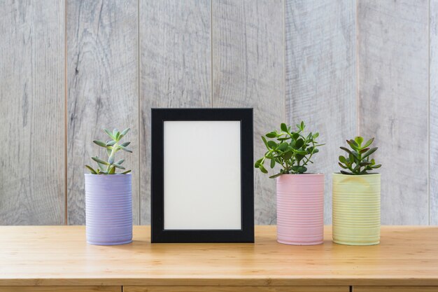 Cadre photo blanc avec des plantes de cactus en boîte peinte sur un bureau en bois