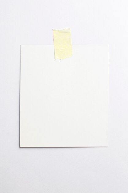Cadre photo polaroid blanc avec des ombres douces et du scotch jaune isolé sur fond de papier blanc
