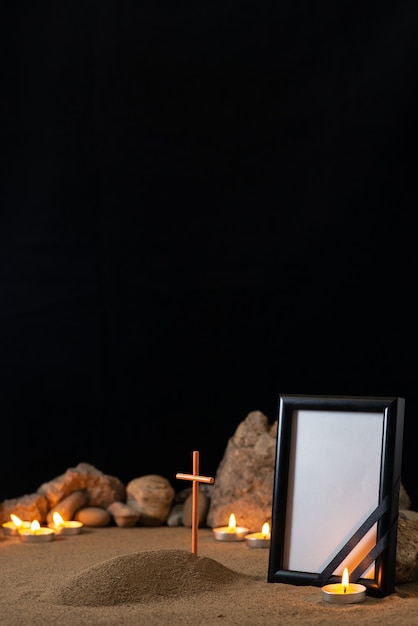 Cadre photo vide avec des bougies en pierres et petite tombe sur la surface sombre