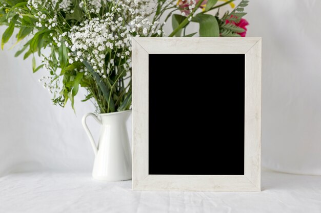 Cadre photo vide vide avec vase à fleur sur tableau blanc