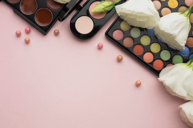 Cadre plat avec fleurs et palettes de maquillage