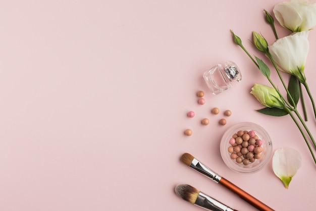 Photo gratuite cadre de pose plat avec des produits de maquillage et des fleurs