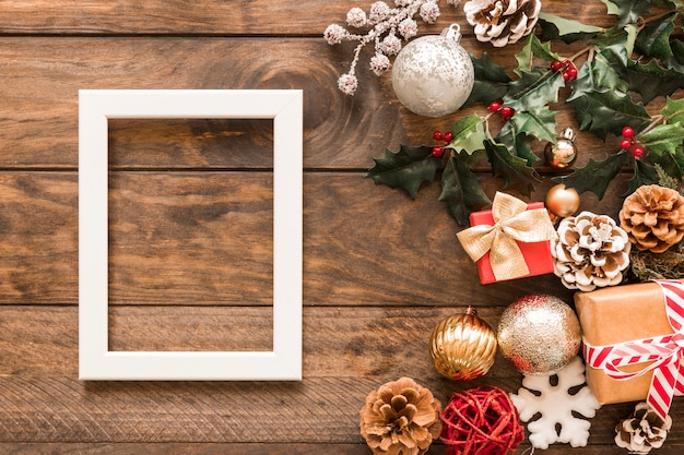 Photo gratuite cadre près de boîtes-cadeaux, de branches vertes, de chicots d'ornement et de boules de noël