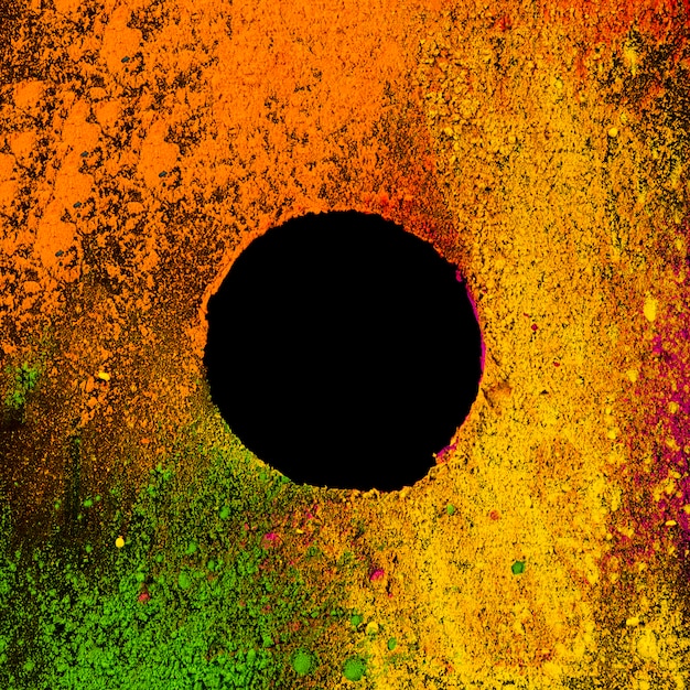 Cadre rond fabriqué dans un cadre de couleurs colorées holi sur une surface noire