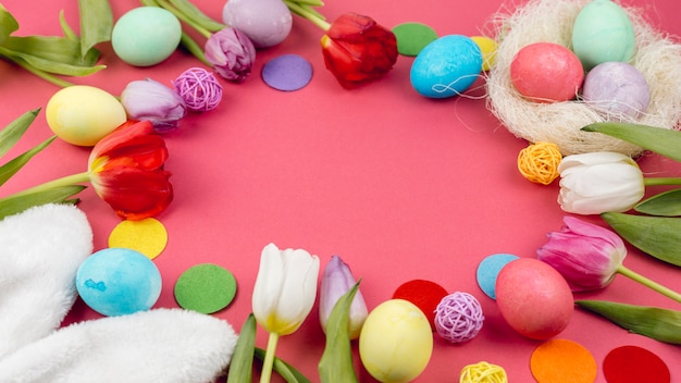 Cadre rond d&#39;oeufs de Pâques et de tulipes sur une table rouge