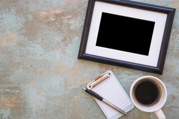 Photo gratuite cadre; tasse à café avec le presse-papier et stylo sur fond rustique