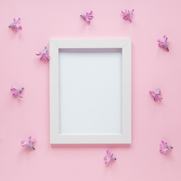 Photo gratuite cadre vierge avec petites fleurs violettes sur table