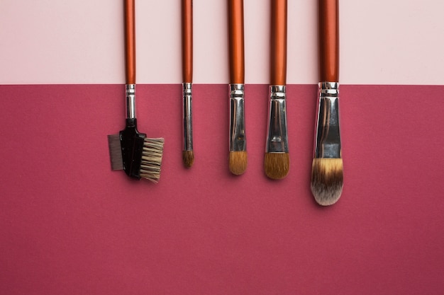 Cadre de vue de dessus avec des pinceaux à maquillage et fond rose