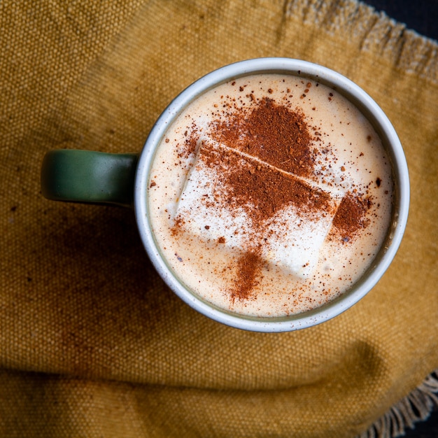 Café au lait doux dans une tasse à plat posé sur un morceau de sac