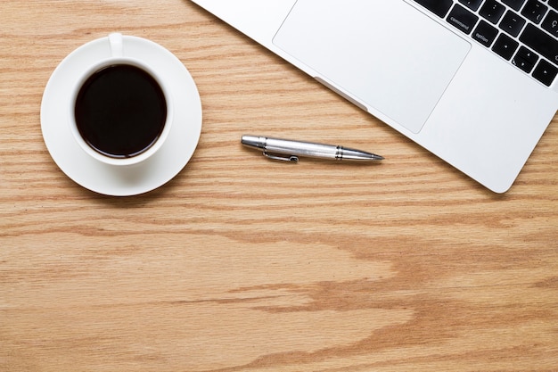 Café à côté d'un stylo et d'un ordinateur portable