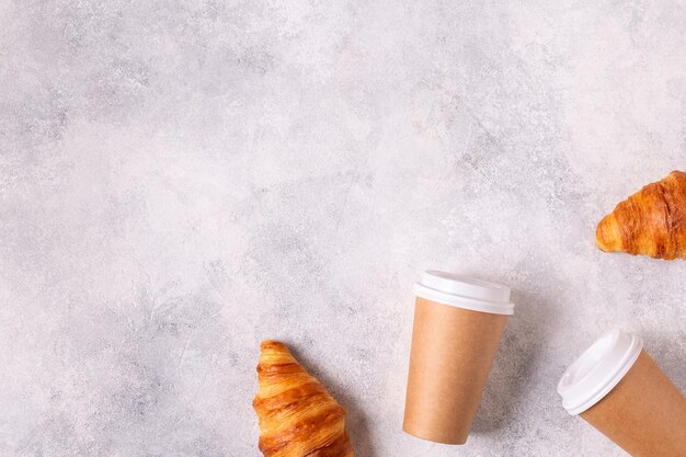 Café à emporter dans une tasse en papier avec croissants, vue de dessus.