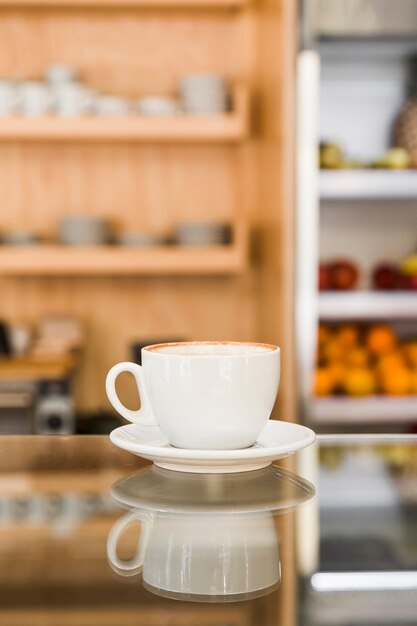 Café frais dans une tasse blanche sur un comptoir en verre