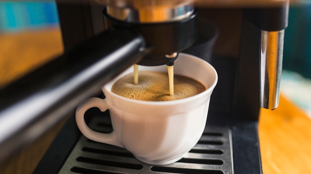 Café avec de la mousse s&#39;échappant de la machine à expresso