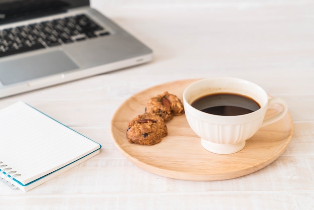 Café noir et biscuits avec ordinateur portable et cahier
