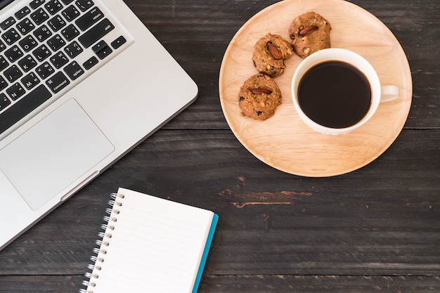 Café noir et biscuits avec ordinateur portable et cahier