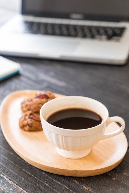 Café noir et biscuits avec ordinateur portable et cahier