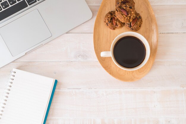 Café noir et biscuits avec ordinateur portable et cahier