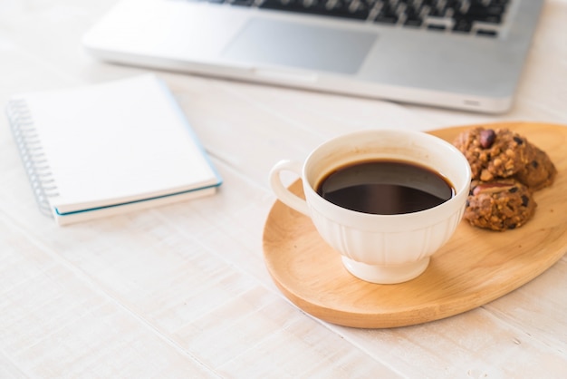 Café noir et biscuits avec ordinateur portable et cahier