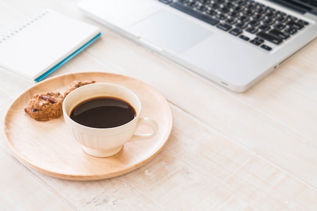 Café noir et biscuits avec ordinateur portable et cahier