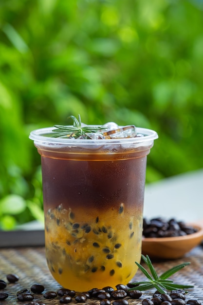 Café noir glacé aux fruits de la passion sur une surface en bois