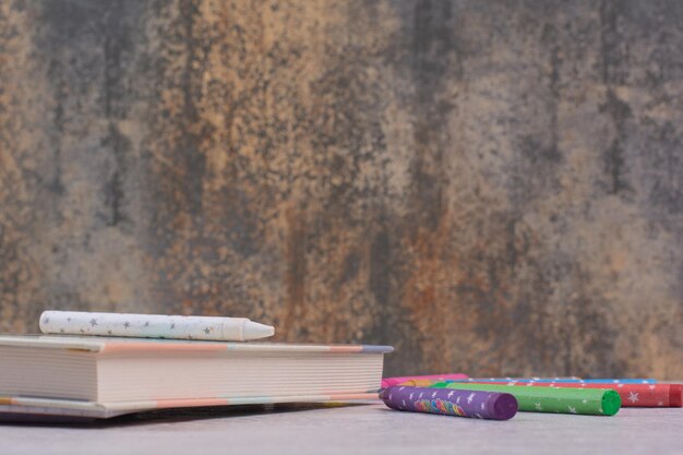 Cahier et crayons colorés sur tableau blanc.