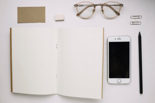 Cahier de croquis ouvert près de smartphone et de lunettes