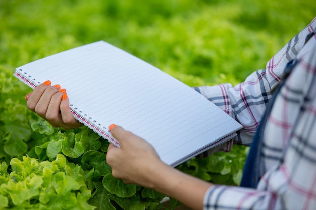 Photo gratuite un cahier entre les mains d'une jeune femme dans la pépinière.