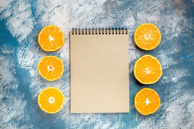 Cahier d'oranges coupées vue de dessus sur une surface blanche bleue