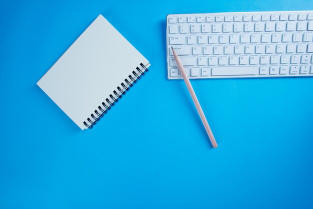 Cahier ouvert avec vue de dessus, crayon sur le bureau bleu