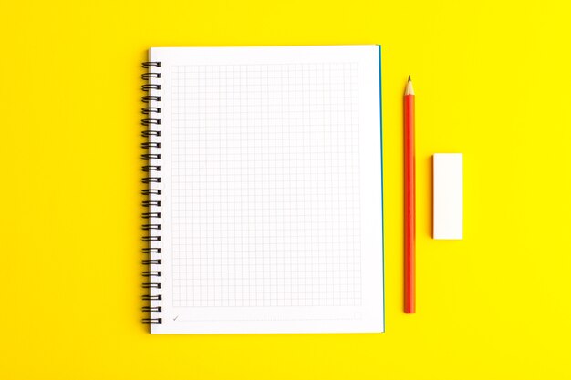 Cahier ouvert vue de face avec un crayon sur une surface jaune