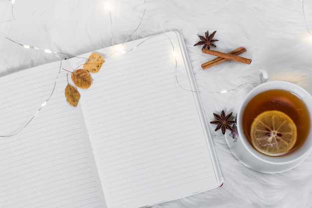Cahier avec une tasse de thé sur un plaid blanc