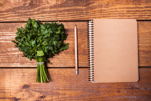 Cahier vierge et crayon avec un bouquet d'herbes sur table en bois