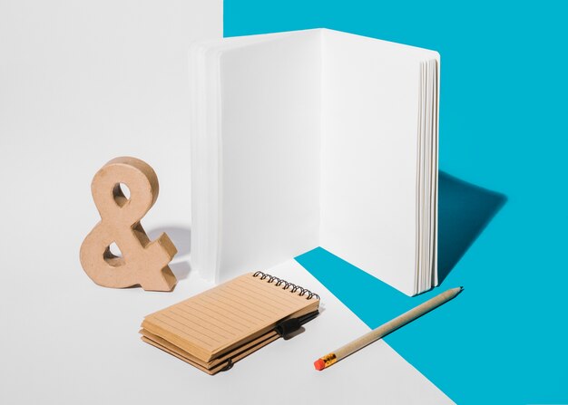 Cahier vierge; symbole de l&#39;esperluette; crayon; et bloc-notes en spirale sur fond blanc et bleu