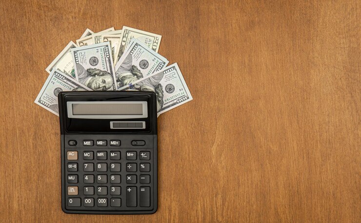 Photo gratuit calculatrice et billets d'un dollar sur un fond plat en bois